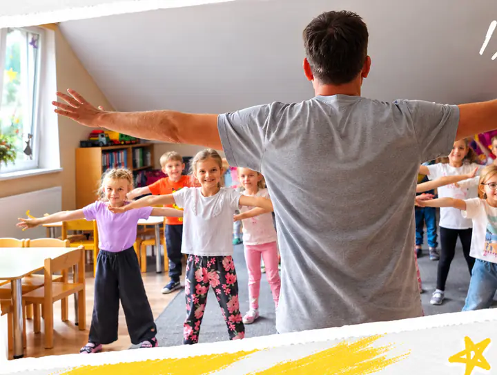 Instruktor ATP Kids rozkłada ręce, a dzieci w przedszkolnej sali powtarzają za nim ten sam ruch